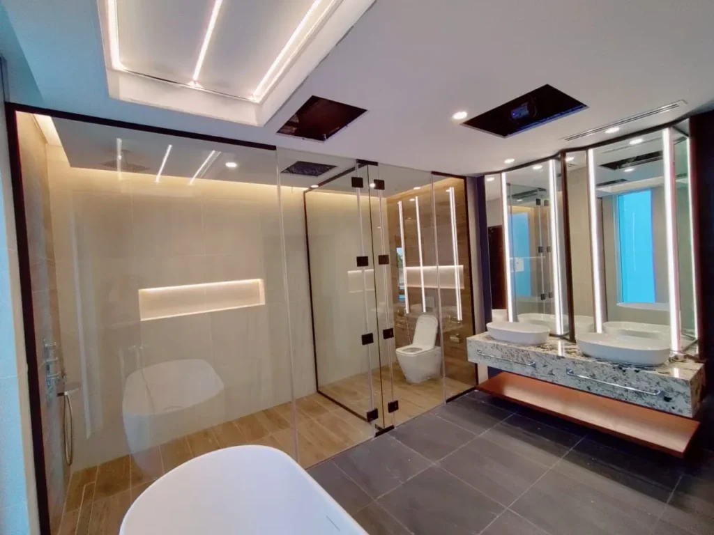 Complete modern bathroom work by SixPointTechnicalServices L.L.C, showcasing a spacious glass shower enclosure, contemporary double vanity with twin sinks, and elegant lighting. Full bathroom renovation and design expertise from SixPointTechnicalServices L.L.C for a luxurious finish.